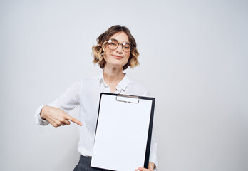 Naklejka premium Business woman holds in her hands a folder with a white sheet on a light background