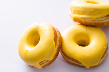 three donuts with banana filling lie on a white background, close-up, delicious breakfast, bright mood
