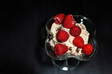 delicious sweet ice cream in a transparent creamer decorated with raspberries on a black...