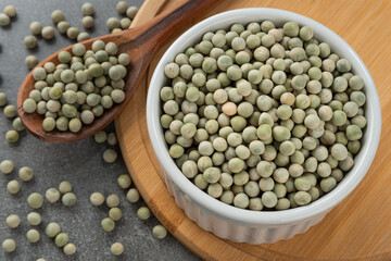 Bowl with whole lentil grains. Detail of wooden spoon and bamboo support.