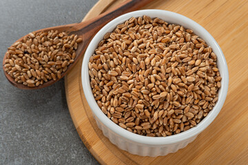Bowl with grains of wheat. Detail of wooden spoon and bamboo support.