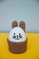 Easter holiday preparation. Crocheted egg basket in the shape of an Easter bunny. Egg stand in the...
