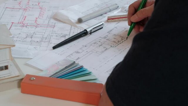 An Asian (Thai) architect is writing a comment on the electrical plan by a pen. In order for the staff to improve.