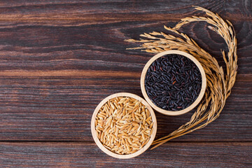 Various types of rice ; black rice and paddy in wooden bowl isolated on wood table 