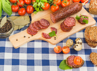 Sliced salami with bread, cherry tomatoes, quail eggs and spices on table