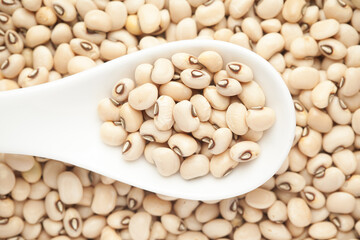 macro Close-up of Organic soybean,  (Glycine max ) or soya bean dal on a white ceramic soup spoon. Top view