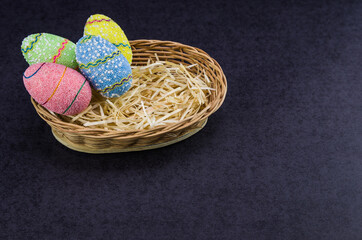 Fototapeta na wymiar Easter colored eggs in a basket isolated on a trendy black background.