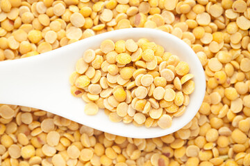 Macro Close-up of Organic arhar dal (Cajanus cajan) on a white ceramic soup spoon. Top view