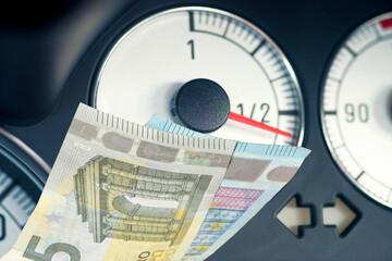 Eine Tankanzeige in einem Auto und Euro Geldscheine