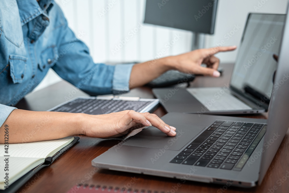 Poster asian programmer woman pointing and looking on multiple laptop screen to writing code and database