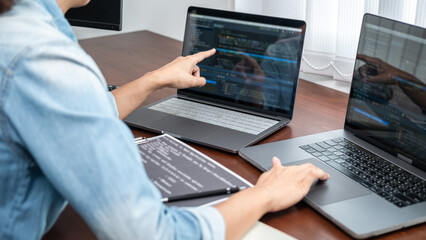 Asian programmer woman pointing and looking on multiple laptop screen to writing code and database