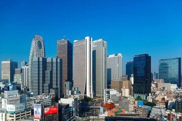 Fototapeta na wymiar City skyline of modern high-rise buildings under blue clear sunny sky in Shinjuku District, Tokyo, Japan ~ Urban scenery of crowded skyscrapers in Downtown Tokyo on a beautiful bright sunny day