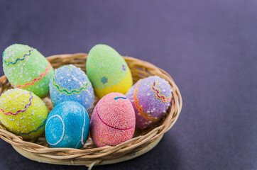Easter colored eggs in a basket isolated on a trendy black background.