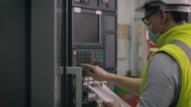 Asian factory worker man operating automated programming CNC milling control machine industry center at tool workshop manufacturing