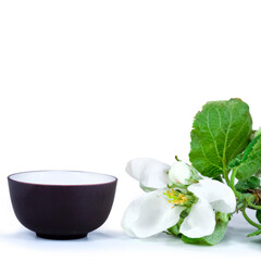 Green tea in a ceramic cup with branches of blossoming apple tree isolated on a white background. 