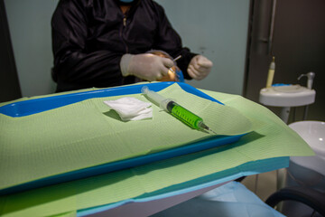 mesa del dentista con jeringa de anestesia, antecedentes de un médico que trata al paciente en tratamiento vocal - obrazy, fototapety, plakaty