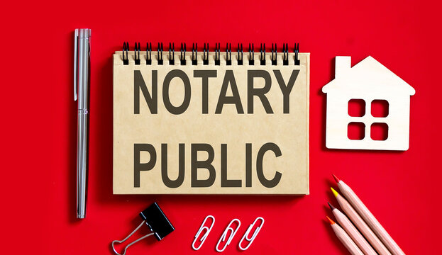 Notary Public text written on a notebook with pencils and office tools and model wooden house