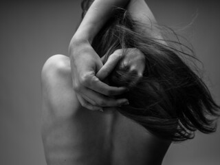 The woman in the gray photograph is touching herself with her bare back