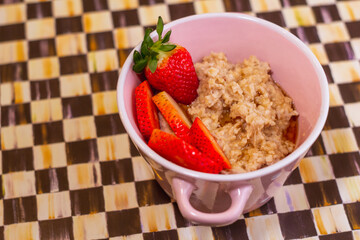 vista detallada de desayuno de avena con fresas frescas en la taza de color rosa de la vendimia, la comida sana en casa