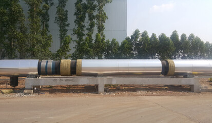 The new black metal pipe with insulated designed to carry pressurized steam is overground parallel to the road.
