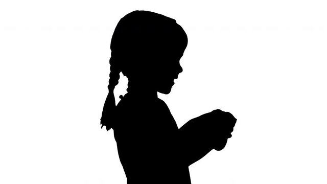 Silhouette Excited little girl play videogame holding joystick in her hands.