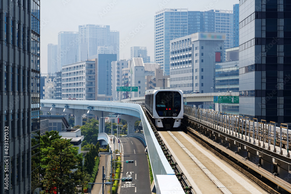 Wall mural scenic view of a train traveling on elevated rails of yurikamome line in downtown tokyo, with a back