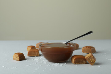 Salted caramel pieces and bowl of sauce on light gray table