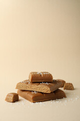 Salted caramel pieces on beige background, space for text