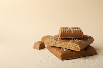 Salted caramel pieces on beige background, space for text
