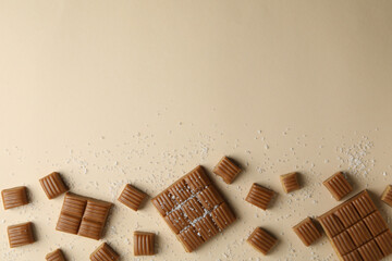 Salted caramel pieces on beige background, space for text