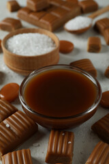 Concept of sweet food with caramel pieces, salt and caramel sauce on white textured background