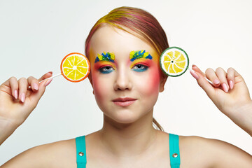 Teenager girl with unusual face art make-up . Child with lollipops in hands on head like ears.