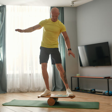 Muscular middle aged man standing on balance board
