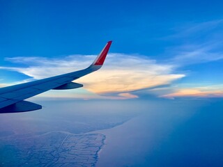 Obraz premium View of airplane wings and golden clouds as background.