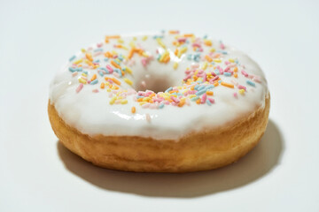 Junk food. Close up shot of a freshly baked delicious donut with colorful sprinkles and white sugar...