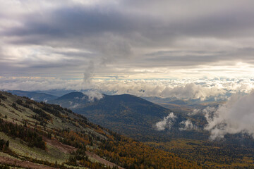 Fototapeta premium autumn in the mountains. view of a mountain valley with beautiful clouds, fog and a small lake-reflecting the sky. very high quality photos
