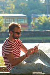 Young adult man using modern smartphone in the park.
