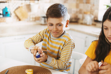 Focused child paints Easter eggs different colors for Easter