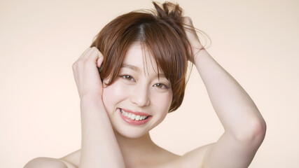 Naklejka premium 髪をくしゃくしゃにするショートヘアの女性 ヘアケアイメージ 