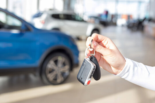 Dealer woman holding keys to a new car. Modern and prestigious vehicles.