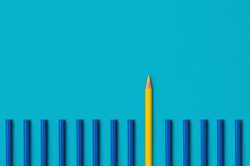 Business leadership concept: a yellow pencil that stands out from a lot of blue pencils. Standing out from the crowd of many identical ones.  Leadership, uniqueness, independence, dissent, think diffe
