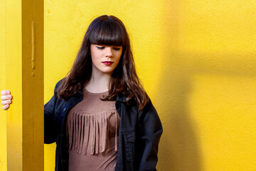 Young brunette girl posing on a yellow background