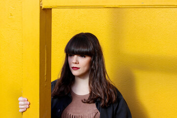 Young brunette girl posing on a yellow background