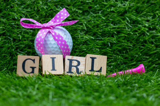 Golf ball with pink ribbon for baby girl on green grass