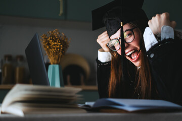 Happy young caucasian woman celebrating college graduation, sitting at front laptop at home during...