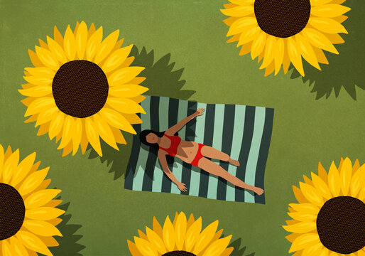 Woman in bikini sunbathing on blanket among large sunflowers
