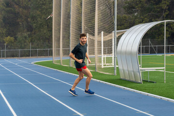 Fototapeta premium Hard working runner practicing in blue running track.