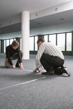 Businessmen measuring and marking floor in new office
