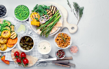 Delicious grilled vegetables with sauces and snacks served on light gray background.