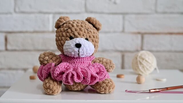 Knitted teddy bear with knitting equipment on the table